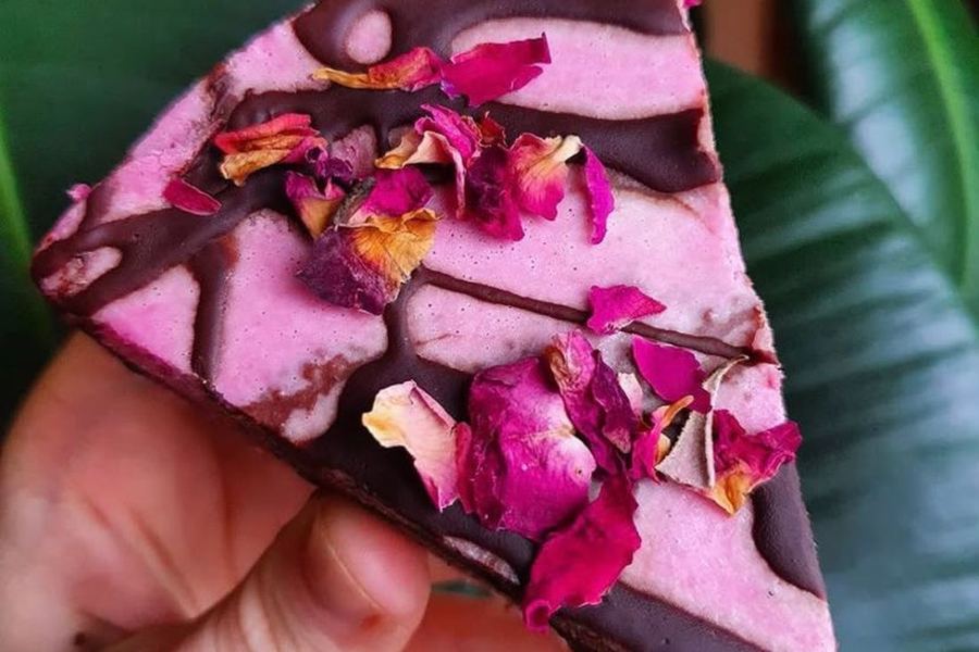 A slice of berry cheesecake topped with dried rose petals.