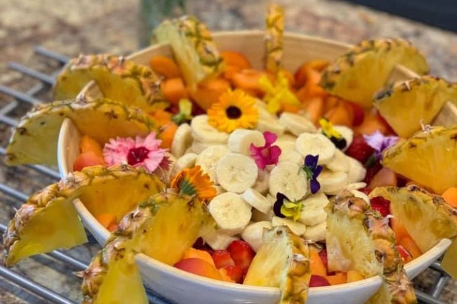 A sharing platter of fresh fruit decorated with edible flowers.