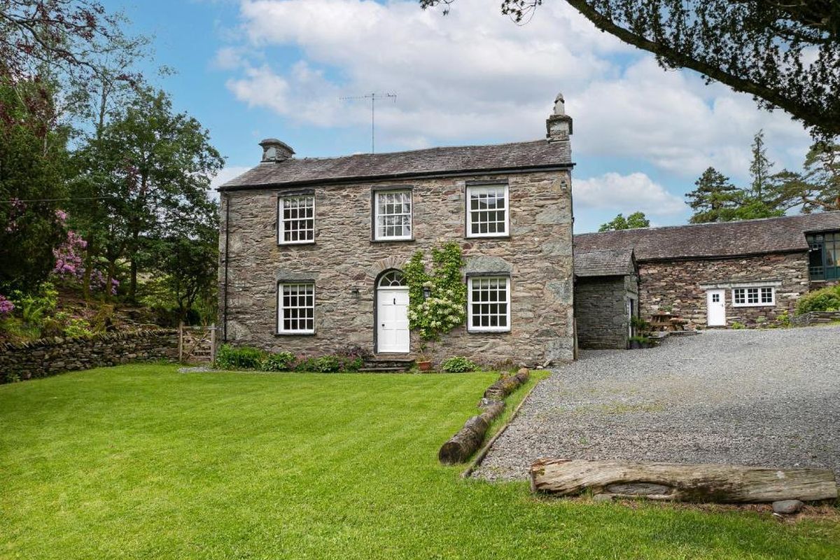 Thorney How, a traditional Lakeland stone house with lawns and fells behind.