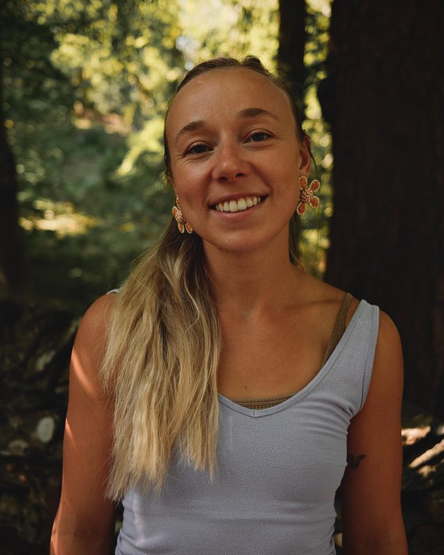 Lydia Marne, your host and yoga teacher, smiling in woodland.