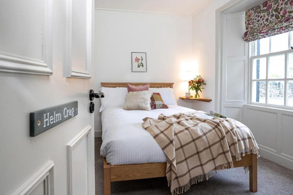 A private ensuite double bedroom with a wooden bed and window seat.
