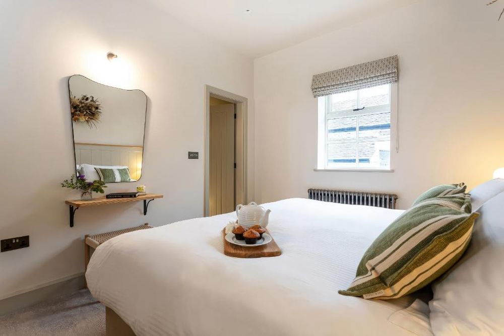 A bright ensuite twin bedroom with white bedding and a window.