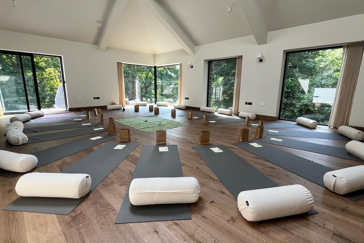 The yoga studio, with mats and bolsters laid out and tall windows looking onto trees.